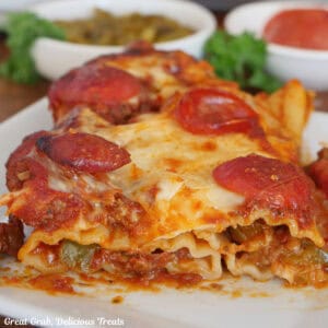 A white plate with a serving of supreme pizza stuffed manicotti on it.