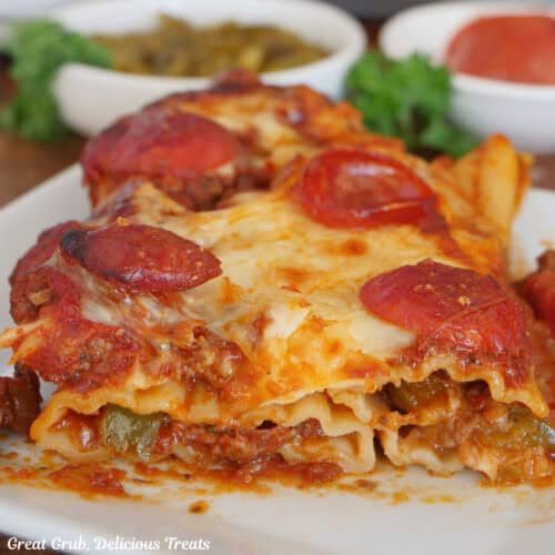 A white plate with a serving of supreme pizza stuffed manicotti on it.
