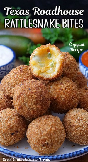 A white plate with blue trim with cheesy, copycat Texas Roadhouse rattlesnake bites on it with a bite taken out of one of them.