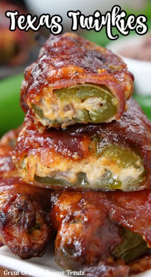 A stack of four stuffed jalapenos wrapped in bacon and one cut in half showing the cheese mixture inside.