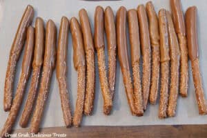 Seventeen pretzel rods covered half way up in caramel placed on parchment paper.