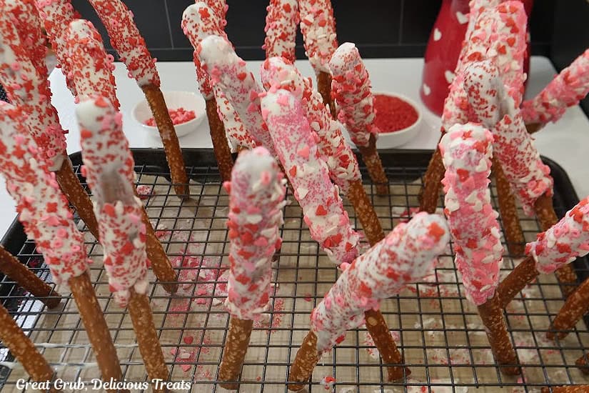 A wire rack with decorated Valentine pretzel rods place in the little openings.