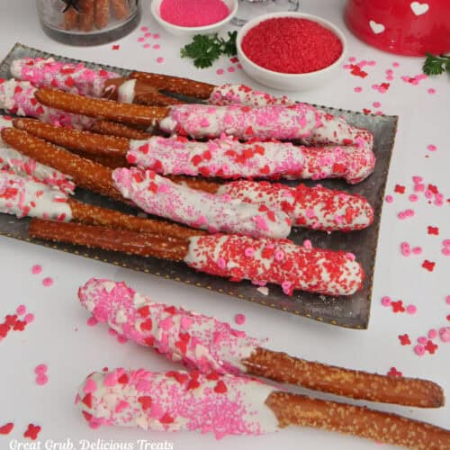 A white surface with pretzel rods decorated with a Valentine theme dessert.