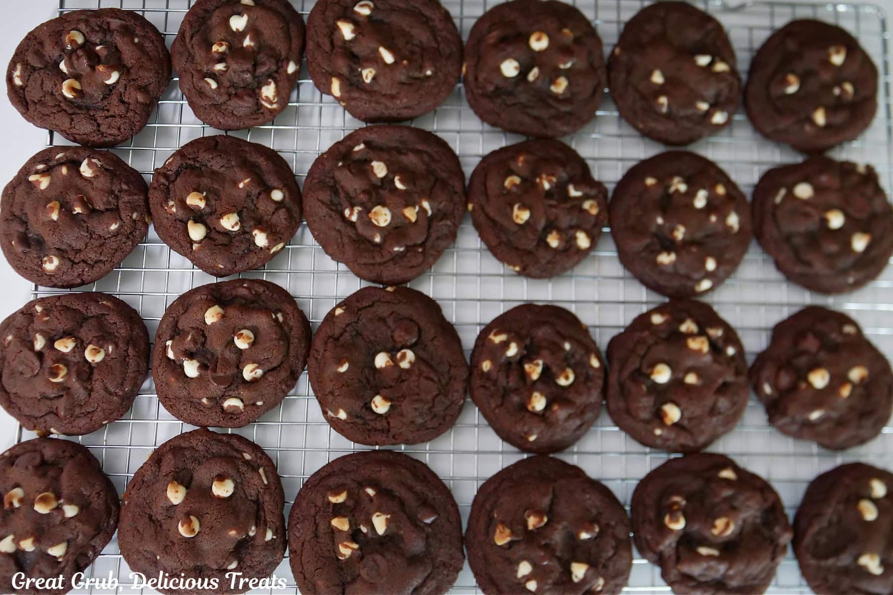 A wire rack with 24 dark chocolate white chocolate chip cookies.
